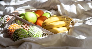 Yatakta meyve ve güneş ışınlarıyla dolu bir torba..