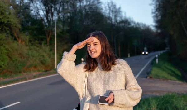 O tânără din apropierea drumului oprește mașina, autostopul. — Fotografie, imagine de stoc