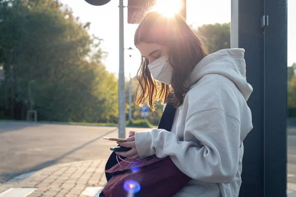 O adolescentă așteaptă un autobuz într-o stație de autobuz dimineața. — Fotografie, imagine de stoc