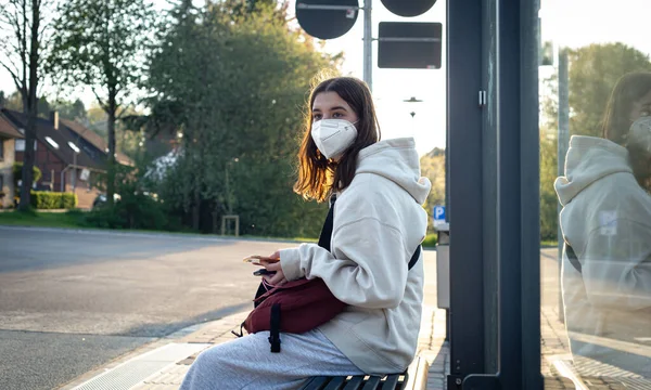 O adolescentă așteaptă un autobuz într-o stație de autobuz dimineața. — Fotografie, imagine de stoc