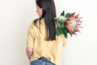 Beyaz arka planda protea çiçeği olan genç bir kadın..