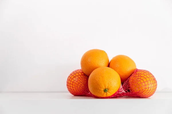 Fresh oranges in a grid on a shelf on a white background. — стоковое фото