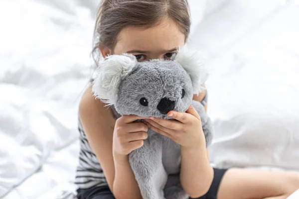 Glückliches kleines Mädchen mit Stofftier-Koala im Bett. — Stockfoto
