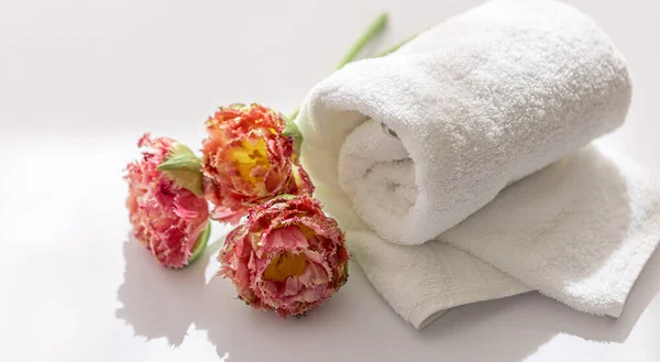 Κοντινές, λευκές πετσέτες μπάνιου terry και λουλούδια. — Φωτογραφία Αρχείου