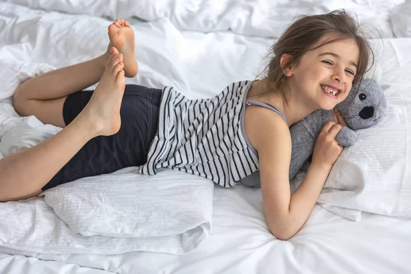 Yatakta yumuşak oyuncak koalası olan mutlu küçük kız..