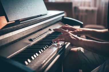 Bir adam karanlık bir odada elektronik piyano çalıyor..