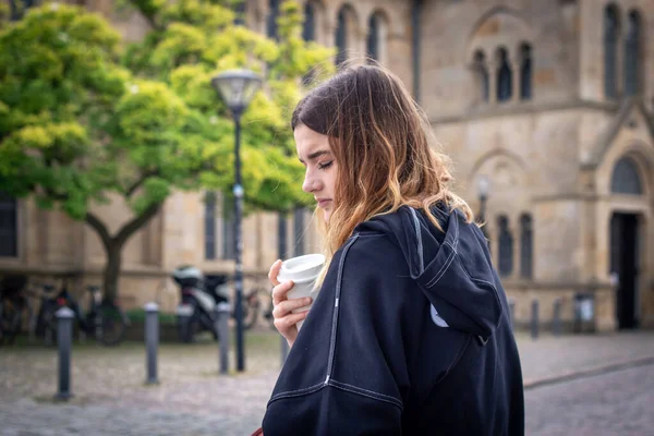 Potret seorang wanita muda yang sedih saat berjalan-jalan dengan segelas kopi. — Stok Foto