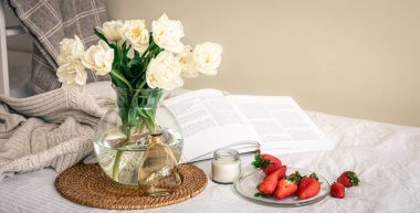 Bir buket çiçek, çilek ve bir kitapla rahat bir kompozisyon..