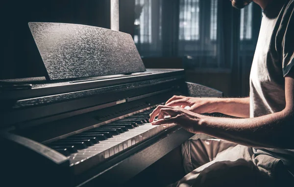 Ein Mann spielt in einem dunklen Raum ein elektronisches Klavier. — Stockfoto
