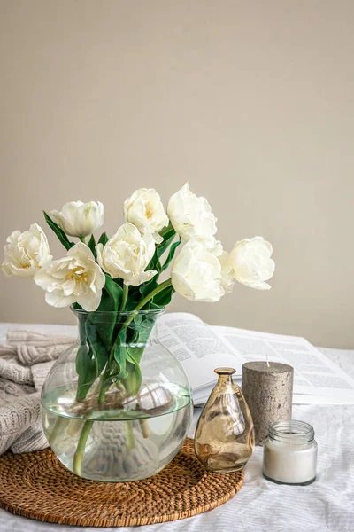 Composición casera con un ramo de tulipanes en un jarrón de vidrio y velas. — Foto de Stock