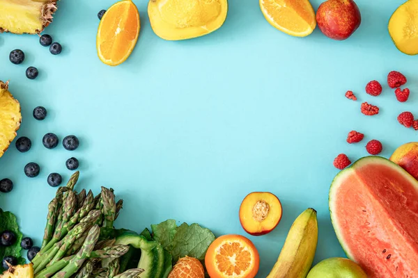 Fruits, berries and vegetables on a blue background, copy space.