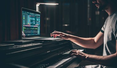 Bir besteci, yapımcı, aranjör, söz yazarı, müzisyen elleri ev stüdyolarındaki bir bilgisayarda müzik düzenleme, müzik prodüksiyonu konsepti.