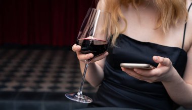 Yakın plan, gece elbisesi giymiş bir kadının elinde bir bardak şarap, bir kutlama konsepti..