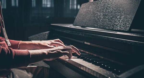 A man plays the electronic piano in a dark room, male hands.