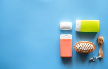 Mavi arka planda duş ve kişisel bakım ürünleri içeren spa kompozisyonu.