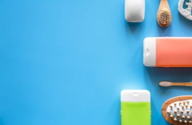 Mavi arka planda duş ve kişisel bakım ürünleri içeren spa kompozisyonu.
