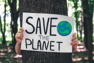 Gezegeni ormandaki kadınların elinde kurtarma çağrısında bulunan poster, doğayla ilgilenme, temizlik, geri dönüşüm ve ekoloji kavramı.