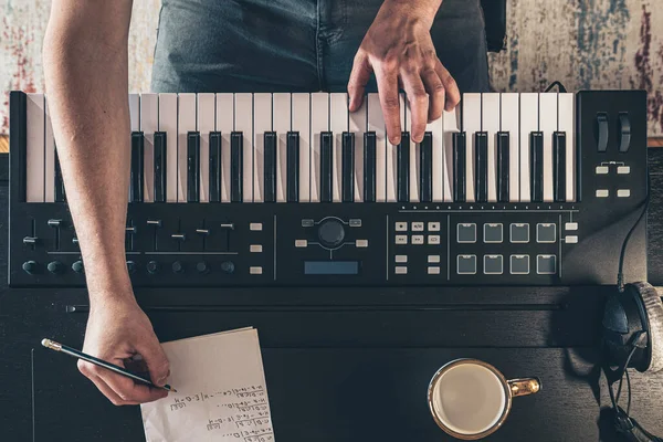 Male musician creates music, top view, piano keys.