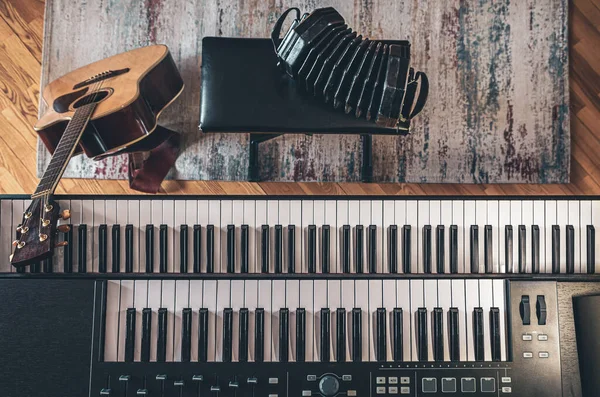 Piano keys, acoustic guitar and other instruments, top view, musicians workplace.