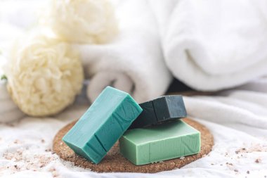 Renkli el yapımı sabunlu spa kompozisyonu havlularla bulanık arkaplan üzerinde yakın plan.