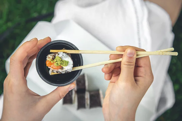 Close up, woman eating sushi in nature, summer picnic concept, maki rolls.