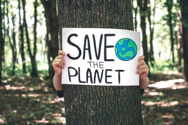Gezegeni ormandaki kadınların elinde kurtarma çağrısında bulunan poster, doğayla ilgilenme, temizlik, geri dönüşüm ve ekoloji kavramı.
