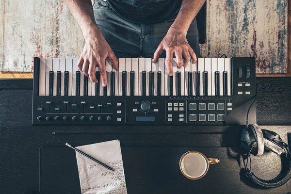 Male musician creates music, top view, piano keys.
