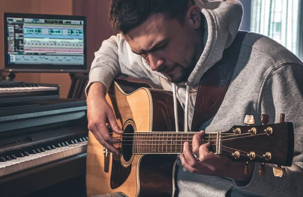 Erkek Müzisyen Evde Bilgisayar Piyanonun Yanındaki Yerinde Akustik Gitar Çalar — Stok fotoğraf