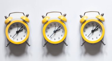 Beyaz zemin üzerindeki sarı alarm saatleri izole, düz konum, zaman kavramı, kavramsal minimalizm.