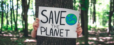 Gezegeni ormandaki kadınların elinde kurtarma çağrısında bulunan poster, doğayla ilgilenme, temizlik, geri dönüşüm ve ekoloji kavramı.