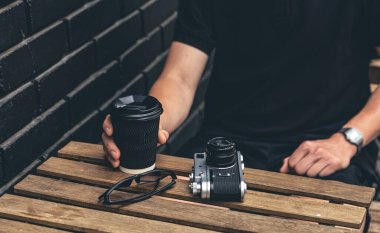 Bir fincan kahve, ahşap masada klasik film kamerası, retro konsept..