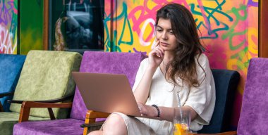 Yazın açık havada bir kafede dizüstü bilgisayarla çalışan çekici genç bir kadın..