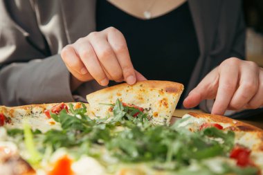 Yakın plan, bir kadın eli bir parça vejetaryen pizza, domates ve roka alır..