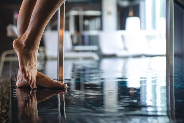 Close-up, a womans foot steps into the pool, the concept of relaxation in the spa complex.