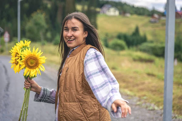 Woman with a bouquet of sunflowers in nature in a mountainous area.