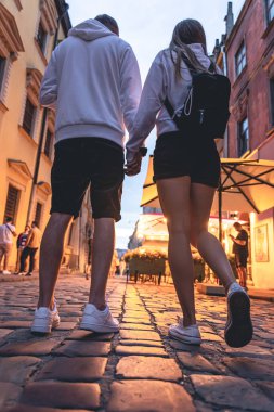 Bir erkek ve bir kadın akşamları şehirde el ele tutuşuyor, eski şehirde yürüyüş, romantizm ve turizm kavramı..