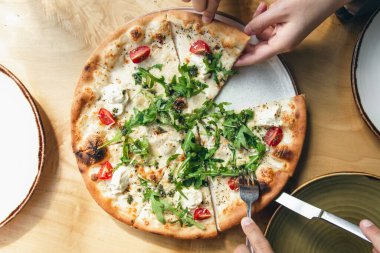 Yakın plan, sebzeli vejetaryen pizza, kiraz domatesleri ve ahşap bir masada roka..