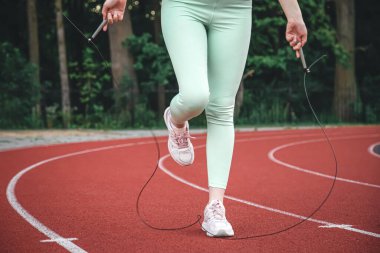 Woman jumping rope in the stadium, weight loss concept.
