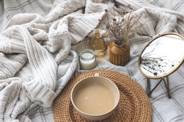 Cozy autumn composition with a cup of coffee, a mirror and candles in the bed.