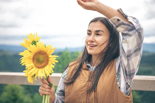 Woman with a bouquet of sunflowers in nature in the mountains, copy space.