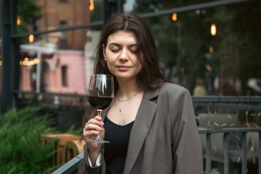 Bulanık arka plan, parti ve kutlama konseptinde restoranın yakınında bir kadeh kırmızı şarapla çekici genç bir kadın..