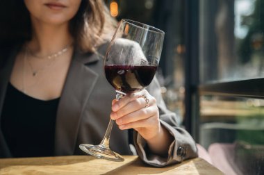 Close-up, a glass of red wine in female hands in a restaurant.
