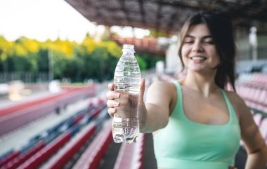 Spor kıyafetleri içinde bir şişe su, spor ve spor konsepti olan genç bir kadın..
