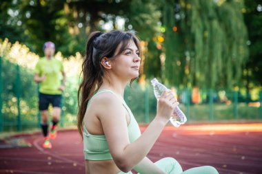 Stadyumda elinde bir şişe su olan genç bir kadın..