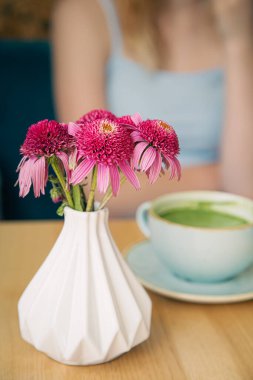 Yakın plan, kafedeki ahşap bir masada yeşil kibritli büyük bir seramik bardak..