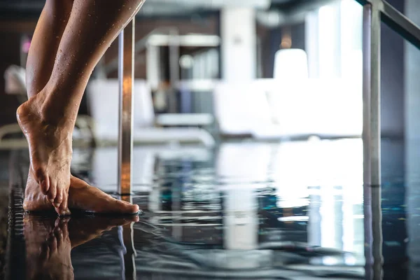 Close-up, a womans foot steps into the pool, the concept of relaxation in the spa complex.