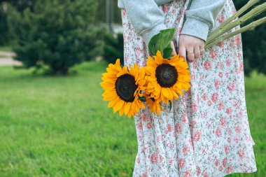 Close-up, a bouquet of sunflowers in female hands on a blurred background in the city, copy space.
