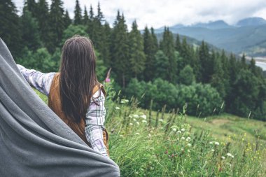 Dağlarda ekoseye sarılı genç bir kadın bulanık bir arkaplanda, boşluğu kopyala.