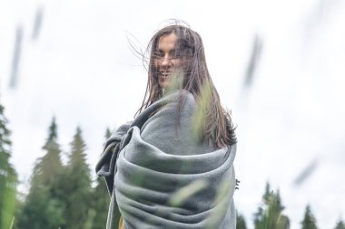 Dağlarda ekoseye sarılı genç bir kadın bulanık bir arkaplanda, boşluğu kopyala.