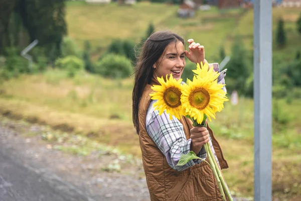 Woman with a bouquet of sunflowers in nature in a mountainous area.